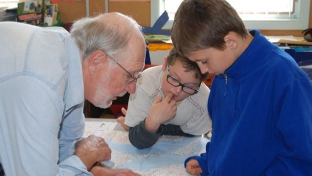 George Brooks helps two Magnetawan Central School students find the Magnetawan River on a map of Ontario. Brooks presented to the primary and junior classes at MCS about fish in the area.