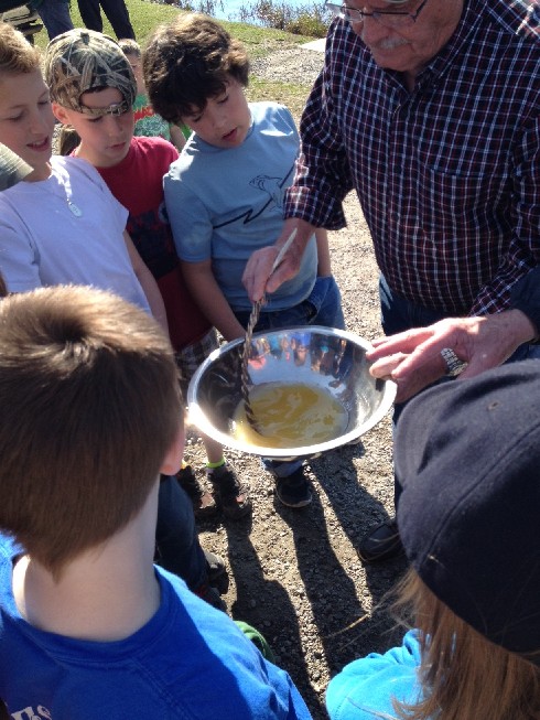 Hatchery member Sam Dunnett ( Mayor) demonstrates how to stir the eggs and sperm for proper fertilization with a feather so not to damage the eggs