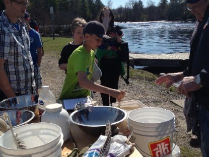 students at the dock helping stir the fertilized eggs before being transferred to the hatchery containers