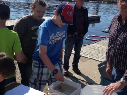 students at the dock helping stir the fertilized eggs before being transferred to the hatchery containers